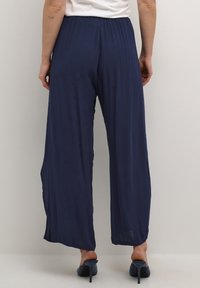 Marineblauwe wijde broek van lichtgewicht stof met een elastische tailleband, voorzien van zijsplitten en een vloeiende snit.