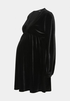 Abito da maternità in velluto nero con scollatura a V, lunghe maniche a palloncino e vita elasticizzata, caratterizzato da una silhouette fluida.