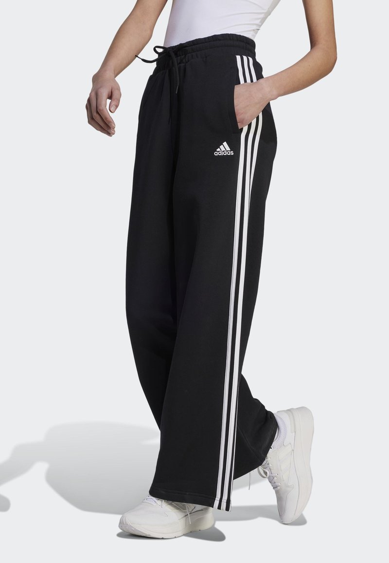 adidas Sportswear - ESSENTIALS STRIPES WIDE PANT - Tracksuit bottoms - black/white, Enlarge