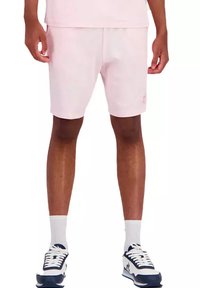 Shorts de sport rose clair en tissu doux, avec une taille élastique et un logo discret sur le côté inférieur.