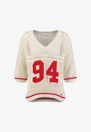 Cremefarbener kurzärmliger Pullover mit offenem Strickmuster und V-Ausschnitt, roter "94" auf der Vorderseite sowie rotem Abschluss an Ärmeln und Saum.