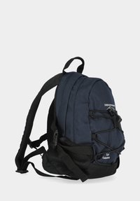 Marine rygsæk med et tekstureret stof, justerbare stropper og en mesh sidelomme. Udstyret med bungee-snore på forsiden for ekstra opbevaringsplads.