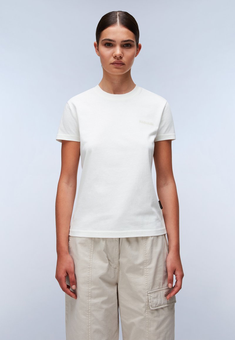 Witte katoenen T-shirt met korte mouwen, ronde hals en een discreet logo in lichtgrijze details op de borst. Gemaakt met beige cargobroeken.