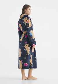 Accappatoio navy con motivi colorati di gatti e stelle, realizzato in materiale morbido. Caratterizzato da un cappuccio e una cintura, con un design fino al polpaccio.