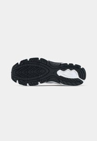 Black rubber sole with a textured grip pattern, featuring white accents and a curved design, suitable for athletic footwear.