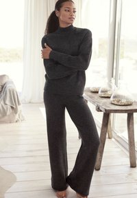 Grau gestrickter Pullover mit hohem Kragen, kombiniert mit passenden weiten Hosen. Weicher, strukturierter Stoff, der für Komfort und Wärme sorgt.
