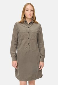 Robe chemise vert olive en mélange de coton, dotée d'une fermeture à boutons sur le devant, de deux poches poitrine et de manches longues avec des poignets à boutons.