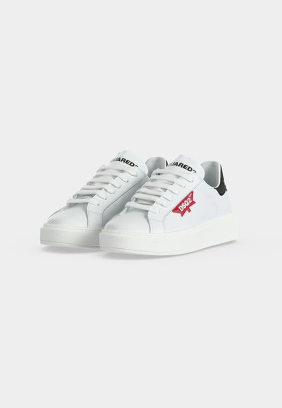 Paire de baskets basses blanches avec lacets blancs, languettes de talon noires et logo DSQ2 rouge sur le côté.