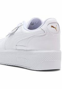 Baskets en cuir blanc avec une semelle en caoutchouc texturé. Présente un accent en or avec le logo Puma et des détails de couture contrastants.