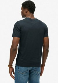 Sort kortærmet t-shirt i en glat bomuldsblanding, med en klassisk rund halsudskæring og en almindelig pasform. Båret med blå denimjeans.