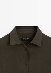 Mørkebrun skjorte med knaplukning og klassisk krave, lavet af letvægtsstof. Har et mærke med "Massimo Dutti" og brune knapper.