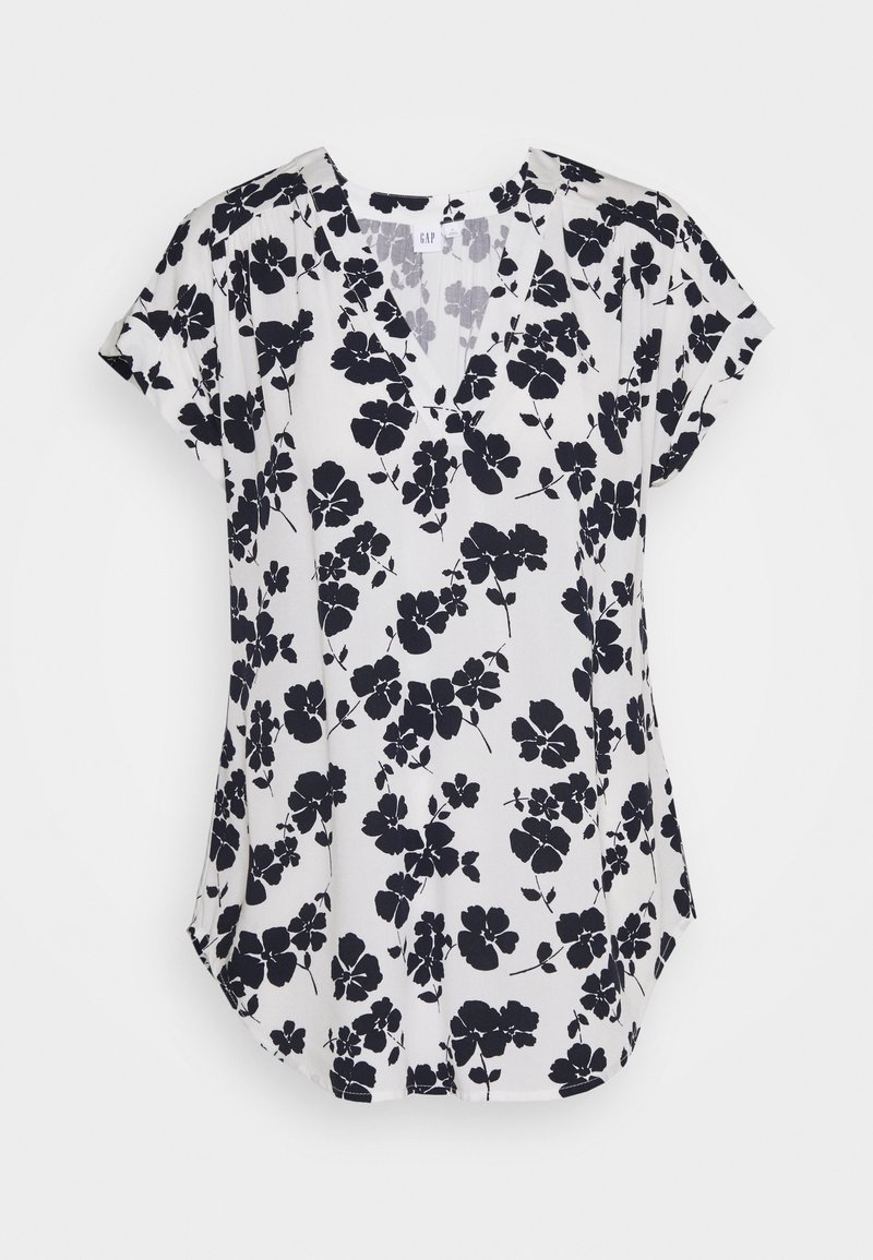 Blouse blanche à manches courtes avec imprimé floral noir et col en V, présentée à plat sur fond blanc.