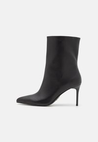 Černé kožené kotníkové boty s špičatou špičkou a stiletto podpatkem. Hladká textura, elegantní design a jednoduchá silueta.
