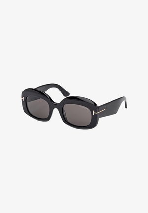 Lunettes de soleil noires surdimensionnées avec une finition brillante, verres carrés et accents dorés sur les branches. Présente un design audacieux et massif.