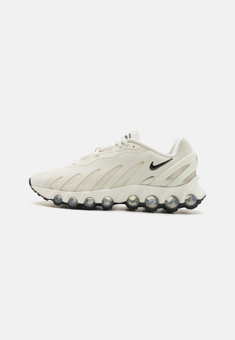 Fehér sportcipő texturált felsőrésszel, hangsúlyos fekete Nike logóval és jellegzetes buborék talppal, amely átlátszó elemeket tartalmaz.