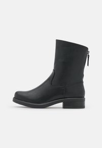Bottine noire en matériau synthétique à texture lisse, tige droite, détail de fermeture éclair latérale et petit talon bloc.