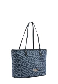 Blå tygkasse med ett geometriskt mönster, svart läderkant, dubbla handtag och en guldfärgad varumärkeslogotyp på framsidan.