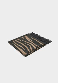 Coperta a righe zebrate nera e beige con bordi frangiati, realizzata in tessuto morbido. Piegata ordinatamente con una texture liscia.