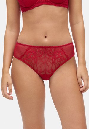 Braguita de encaje rojo con bordado floral, paneles transparentes con lunares y una cintura suave. La tela tiene una textura delicada y un diseño intrincado.