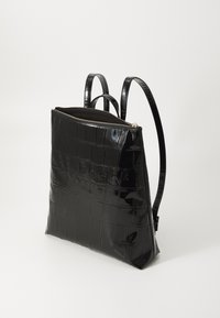 Mochila negra de piel sintética de cocodrilo con acabado brillante, con cierre de cremallera, logotipo en relieve en la parte frontal y dos asas ajustables.