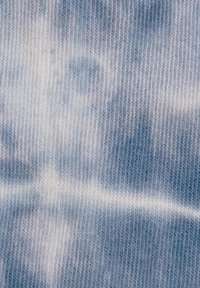 Hellblauer Denim-Stoff mit einer weichen Textur, der ein dezentes Batikmuster in unterschiedlichen Blau- und Weißtönen aufweist.