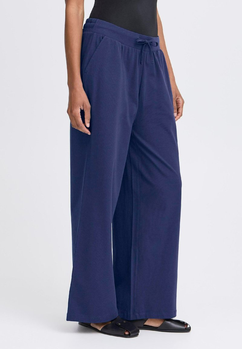 Navyblauwe wijde-pijpen broek van zachte stof, met een elastische tailleband met een trekkoord en zijzakken. Platte voorkant ontwerp.