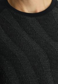 Maglione nero con trama a coste, caratterizzato da un collo a giro nero solido. Il materiale sembra morbido e leggermente lucido.