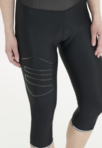 Svarta träningsleggings i stretchigt material, med ett meshpanel och texturerade detaljer på sidan för ökad grepp och stil.