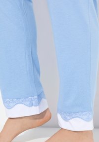 Ljust blå pyjamasbyxor med vita manschetter som har scalloped spetskant. Mjuk bomullsmaterial med en slät textur.