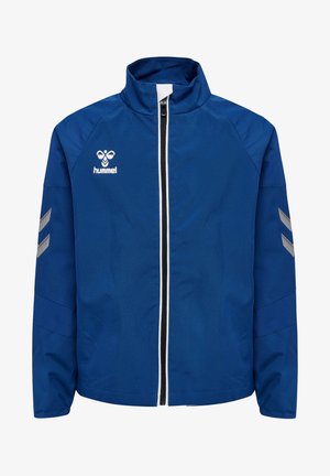Blauwe sportjas met volledig ritssluiting aan de voorkant, witte en zwarte ritstrekker, reflecterende chevrons op de mouwen en wit hummel-logo op de borst.