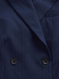 Mørkeblå dobbeltradet blazer lavet af blødt stof, med subtile striber, to runde sorte knapper og en sidelomme.