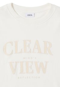 Sweatshirt crème avec un col côtelé portant un texte en relief beige : "RÉFLEXION DE L'ESPRIT CLARIFIER." Texture simple et lisse. Étiquette de marque : CECIL.
