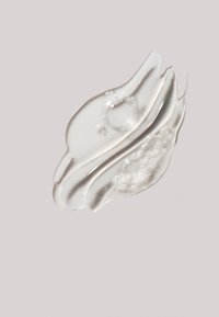 Transparent gel-liknande produkt med en glansig yta, som har bubblor och en mjuk textur. Tillämpad på en mjuk, ljus bakgrund.