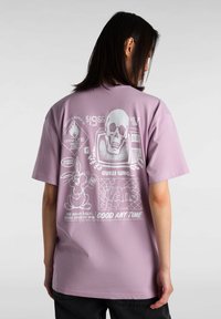 Camiseta de color lavanda claro con impresiones gráficas blancas, que incluyen una calavera, un conejo y texto. Corte holgado con mangas cortas y escote redondo.