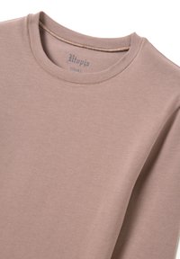 Lichtroze langemouwen shirt van zachte stof, met een ronde hals en een klein gedrukt label met de tekst "Utopia XS."