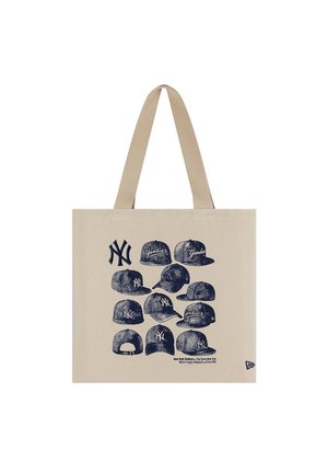Béžová taška na rameno s námorníckomodrými náčrtmi čiapok a log New York Yankees, vrátane textu odkazujúceho na baseballový tím od roku 1903.