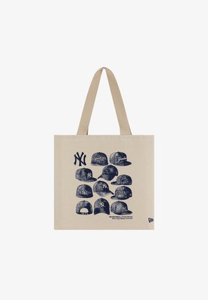 Bézs színű válltáska sötétkék New York Yankees sapkák és logók vázlataival, beleértve a baseballcsapat 1903-as alapítására utaló szöveget.