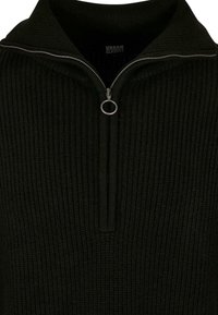 Sweat à zip noir avec une texture côtelée. Doté d'un col montant et d'une fermeture éclair métallique avec un tirette circulaire. Tissu en tricot doux.