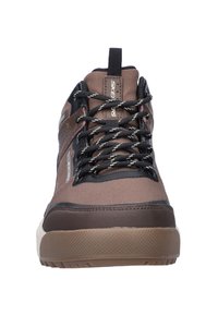 Bruine waterdichte wandelschoen met een gestructureerd oppervlak, zwarte accenten en een versterkte neus. Beschikt over patroonveters en een dikke rubberen zool.