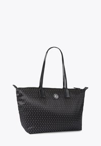 Borsa tote in tessuto nero con pois bianchi, doppi manici in pelle nera, chiusura con zip e un logo rotondo decorativo sul davanti.