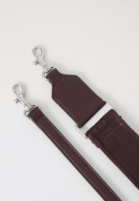 Bordeaux kleurige band gemaakt van gestructureerde stof en leer, met zilveren metalen clips, voorzien van sterke stikdetails en een gladde afwerking.