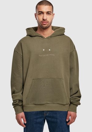 Olive green hoodie made of soft fabric, featuring a front pocket and the text "NOT IN THE MOOD" above two dots. Loose fit with a large hood.