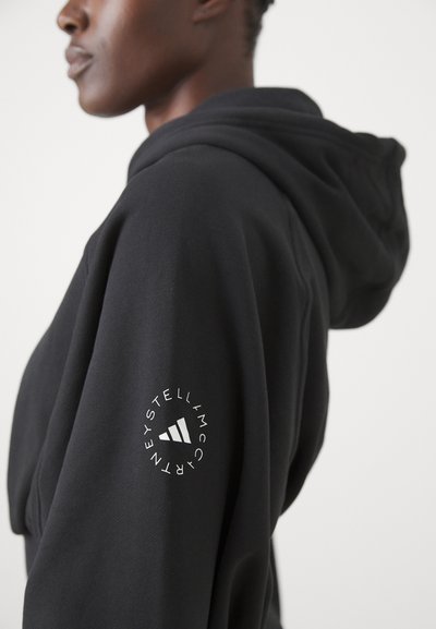 Felpa nera con una consistenza morbida, caratterizzata da un logo bianco prominente sulla manica, progettata con una vestibilità comoda e cappuccio regolabile.