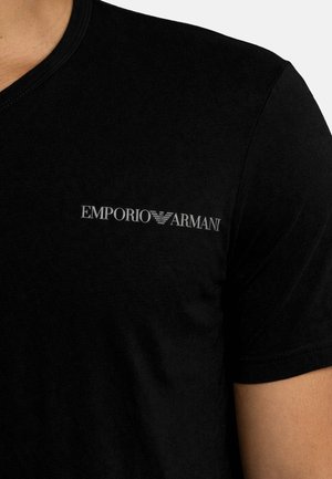 Maglietta nera a maniche corte con logo Emporio Armani e stemma dell'aquila ricamati sulla parte superiore sinistra del petto.