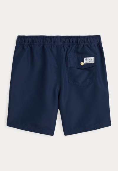 Calções de banho azul marinho com uma cintura elástica, apresentando um único bolso traseiro com fecho de botão e um detalhe de etiqueta. Textura de tecido suave.