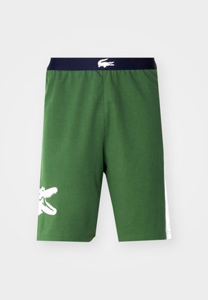 Păshorturi verzi din bumbac cu un tiv negru și un logo alb de crocodil; caracteristici includ accente laterale albe și un design cu o croială confortabilă.