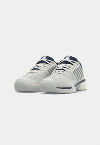 Încălțăminte sport ușoară de culoare albă cu nuanțe de bleumarin. Dispune de un superior texturat cu panouri de ventilație și o talpă căptușită pentru suport.