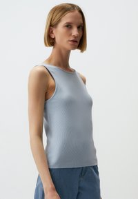 Hellblaues, ärmelloses, geripptes Tanktop mit rundem Halsausschnitt, figurbetontem Design und glatter Textur, kombiniert mit blauen Jeans.