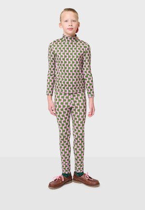 Musterhaftes Kinderoutfit bestehend aus einem Oberteil mit Stehkragen und einer Leggings in pinken und grünen geometrischen Designs, kombiniert mit braunen Schuhen mit pinken Schnürsenkeln.