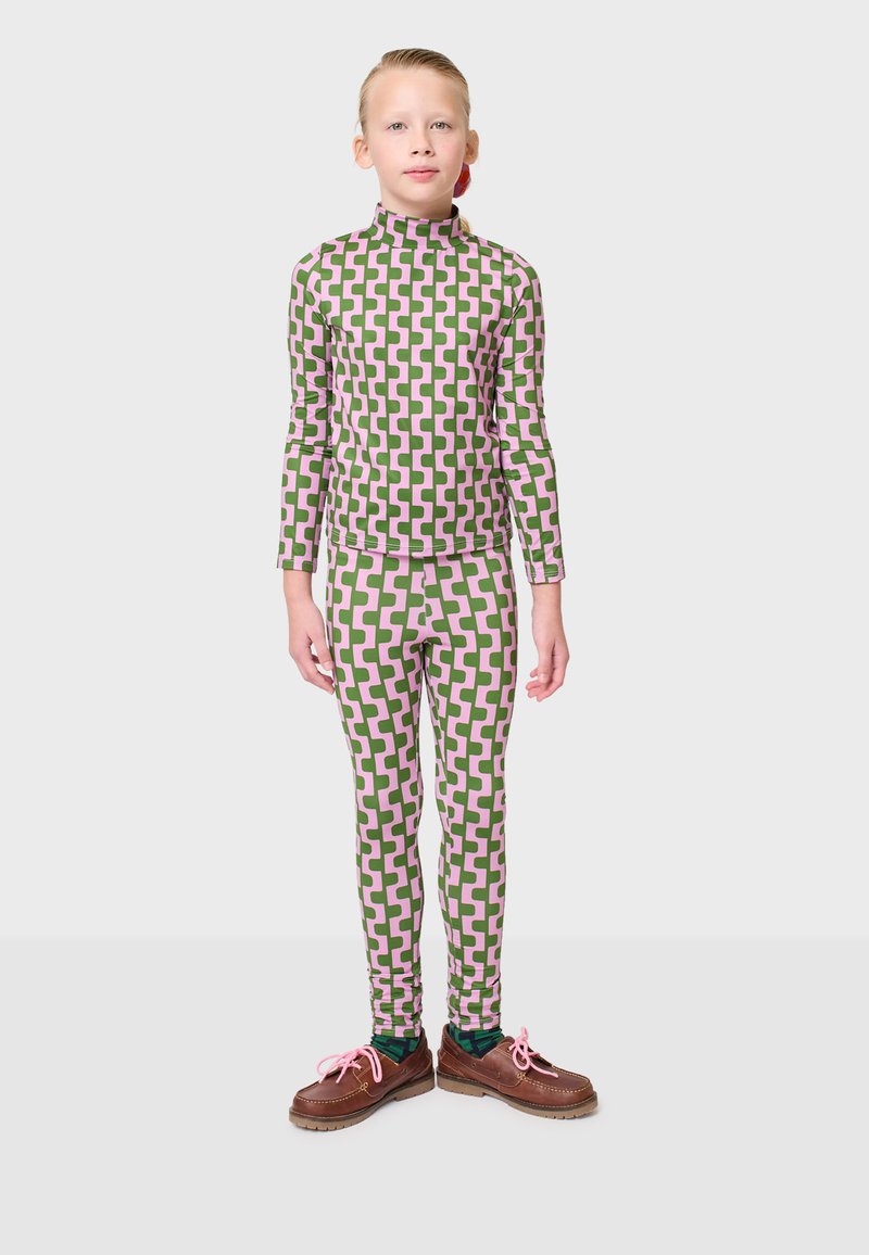 Musterhaftes Kinderoutfit bestehend aus einem Oberteil mit Stehkragen und einer Leggings in pinken und grünen geometrischen Designs, kombiniert mit braunen Schuhen mit pinken Schnürsenkeln.